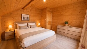 A wooden cabin bedroom with a bed, bedside tables, a dresser, and a framed picture on the wall. - Apt or chalet near the slopes Les Orres (Les Orres)