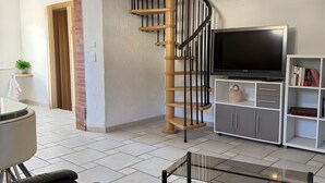Ein Wohnzimmer mit Fernseher, Sofa und einer Treppe.