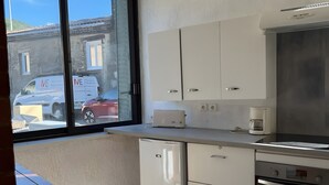 Eine Küche mit weißen Schränken, einem eingebauten Backofen und einem Fenster mit Blick auf eine Straße.