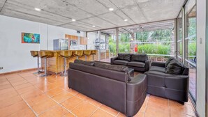 Ein geräumiger Wohnbereich mit einer großen Couch, einer kleineren Couch und einer Bar mit Hockern.