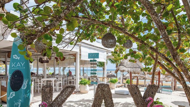 A beach club with outdoor seating, a sign for 'KAY BEACH CLUB,' and a view of the beach. - Design Villa · Tulum Country Club · PGA Golf (Gran Bahía Príncipe)