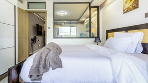 Ein Hotelzimmer mit einem großen Bett, einem Spiegel, einem Fernseher und einem Kleiderschrank.