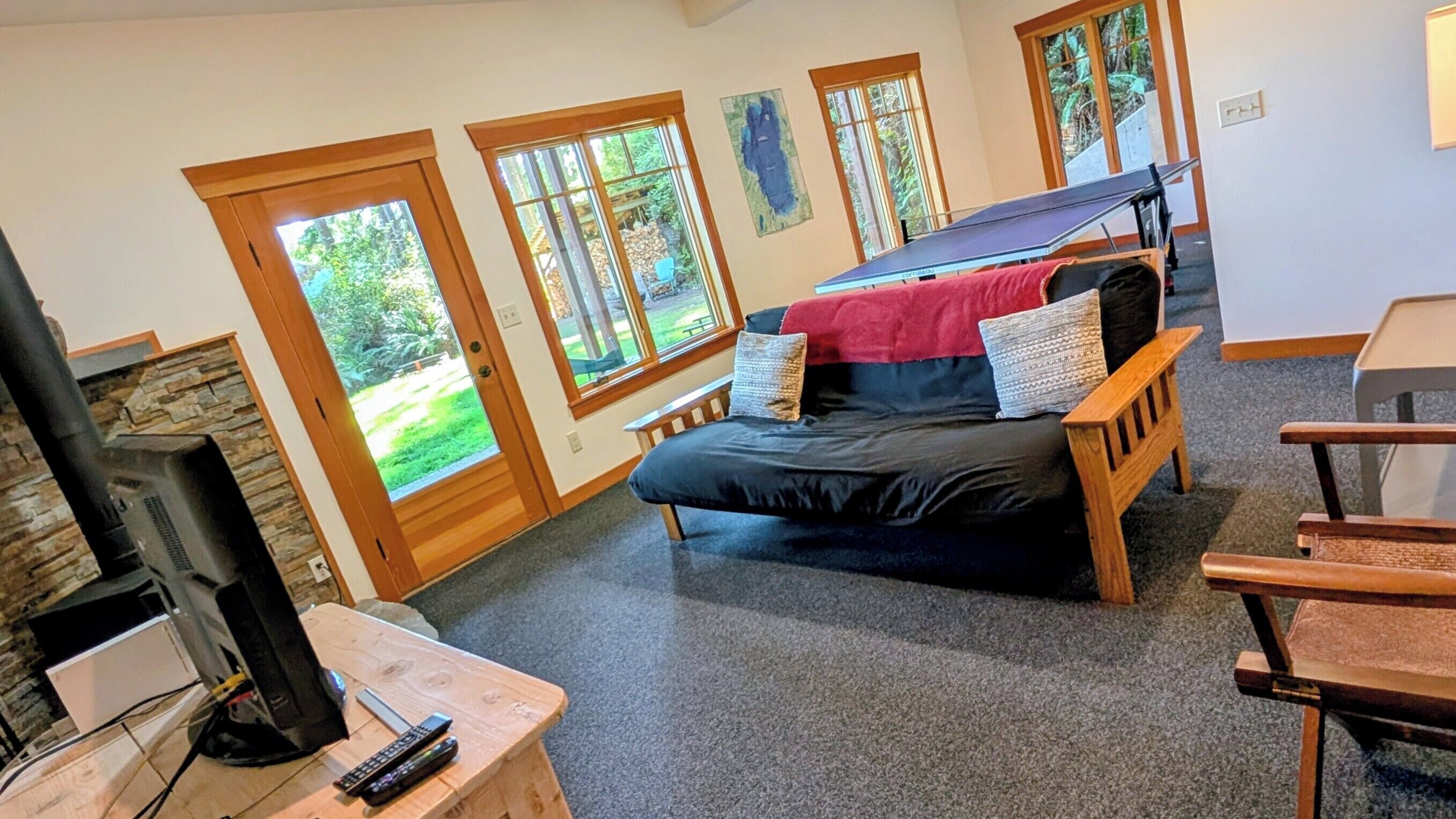 Een gezellige kamer met een bed, een televisie en een open haard. Er zijn grote ramen en uitzicht op het omliggende landschap.