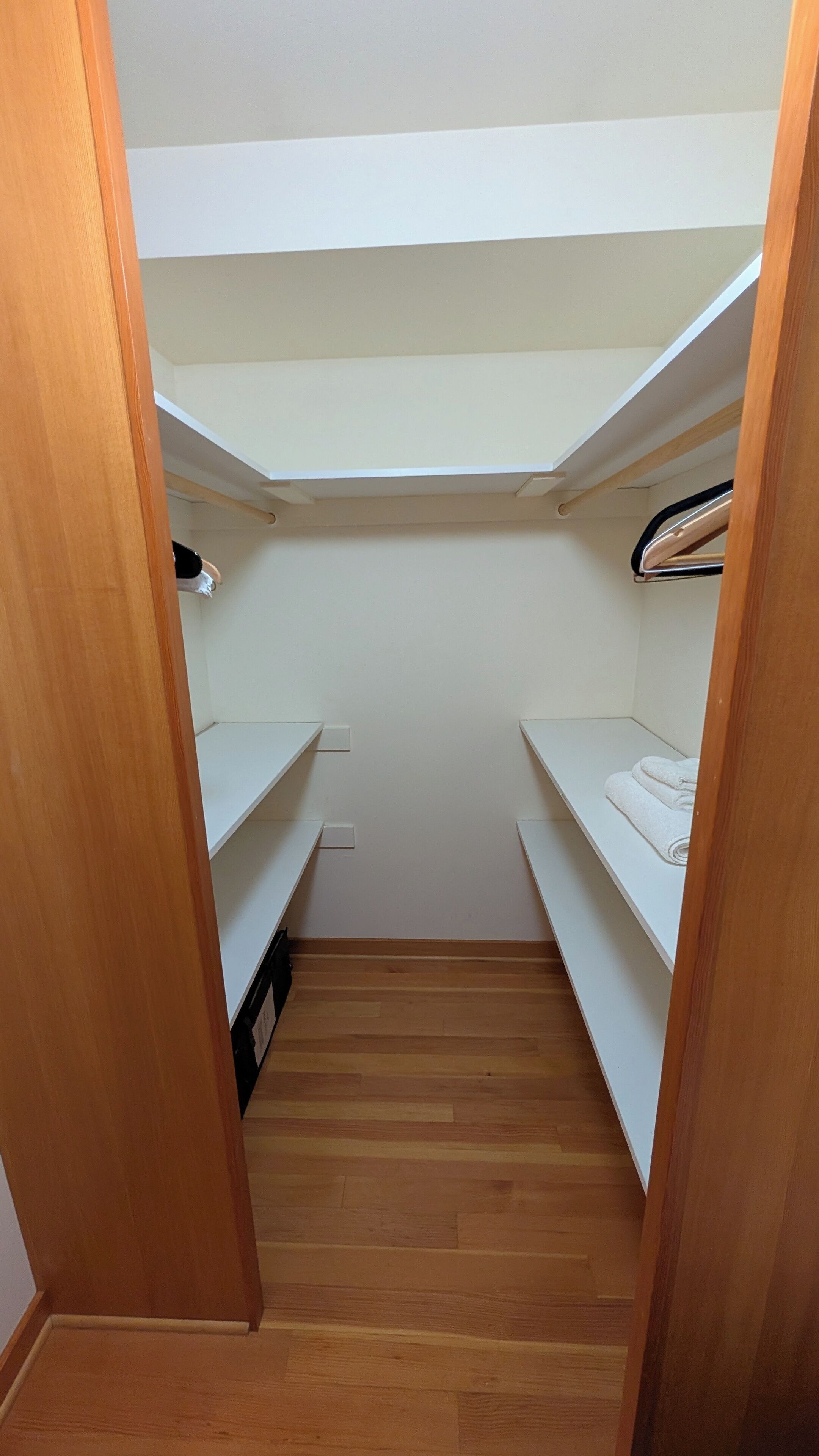 Ein schmaler Durchgangsschrank mit Holzboden und weißen Regaleinheiten.