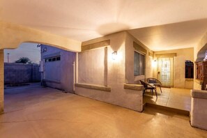 A spacious covered patio area with a concrete floor, a seating area with chairs, and a door leading to an interior space. - Remodeled 2BR Central PHX Gem w/ Free Parking (Phoenix)