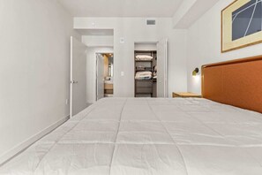 Une chambre à coucher avec un grand lit, une tête de lit en bois, une armoire avec des étagères et un tableau encadré au mur.