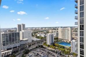 Un immeuble de grande hauteur, avec de nombreux étages, un parking et un court de tennis visible au loin.