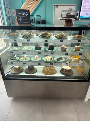 A display case with various desserts and sandwiches, a sign indicating wifi availability, and a chalkboard menu. - Beachfront condo w/ Gym & Direct beach access (Hollywood)