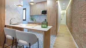 Eine moderne Küche mit Holzausstattung, einer Edelstahl-Mikrowelle und einer Bar mit zwei Stühlen.
