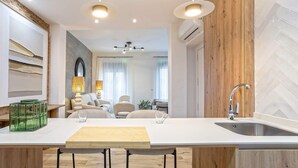 Eine moderne Küche mit einer zentralen Kochinsel, Barhocker, Spüle und einem Essbereich mit einer Couch und Stühlen.