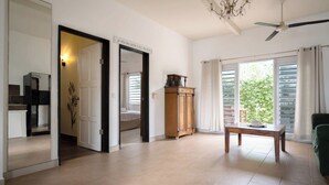 Ein geräumiger Wohnbereich mit Holzschrank, Tisch und Deckenventilator.
