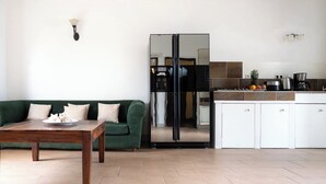 Eine moderne Küche mit weißen Schränken, einem grünen Sofa und einem Holztisch.
