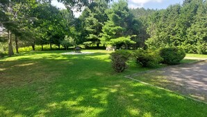 A well-maintained lawn with a gazebo, surrounded by dense trees and a parked car. - La Maison Hacquard (4BR) - 35 min from Mont-Tremblant, Perfect for Families (St-Emile de Suffolk)