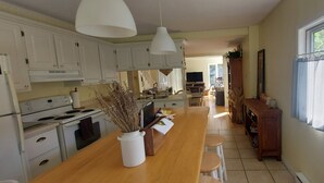 A kitchen with white cabinets, a wooden countertop, and a vase of dried flowers. - La Maison Hacquard (4BR) - 35 min from Mont-Tremblant, Perfect for Families (St-Emile de Suffolk)