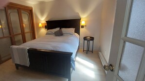 A bedroom with a bed, two bedside lamps, a small table, and a door. - La Maison Hacquard (4BR) - 35 min from Mont-Tremblant, Perfect for Families (St-Emile de Suffolk)