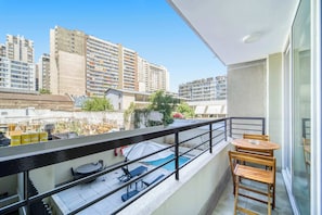 A balcony with a pool, outdoor furniture, and a view of surrounding high-rise buildings. - Central Isabel I - Modern apartment Pool, AC & Wifi (Santiago)