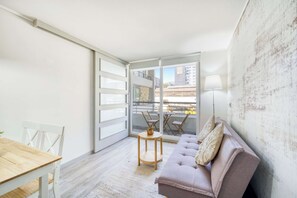 Uma sala de estar moderna com um sofá, uma mesa redonda pequena e uma mesa de jantar.