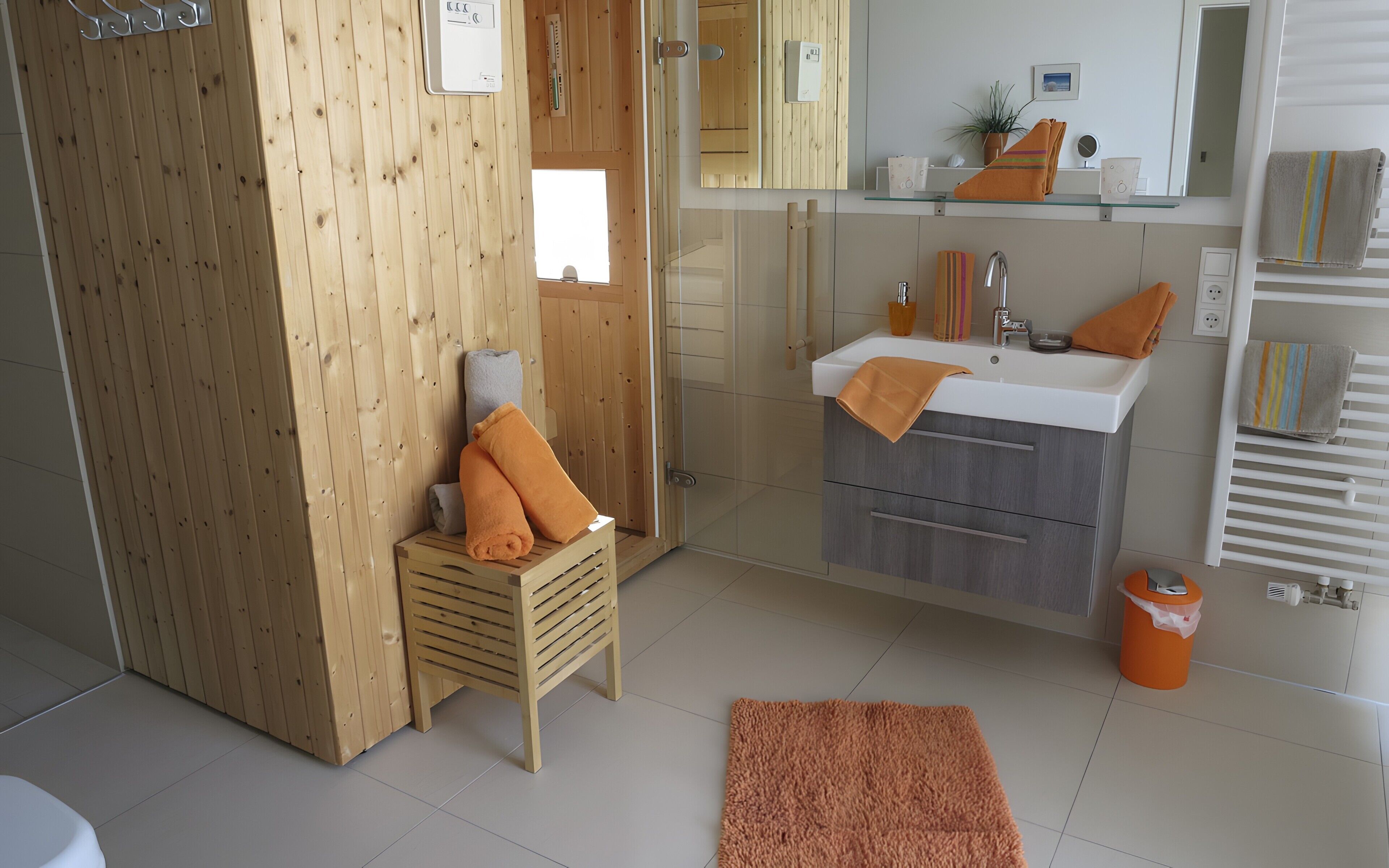 Ein Badezimmer mit Duschkabine aus Holz, einem Waschbecken mit Spiegel und einem Handtuchhalter.