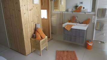 Ein Badezimmer mit Duschkabine aus Holz, einem Waschbecken mit Spiegel und einem Handtuchhalter.