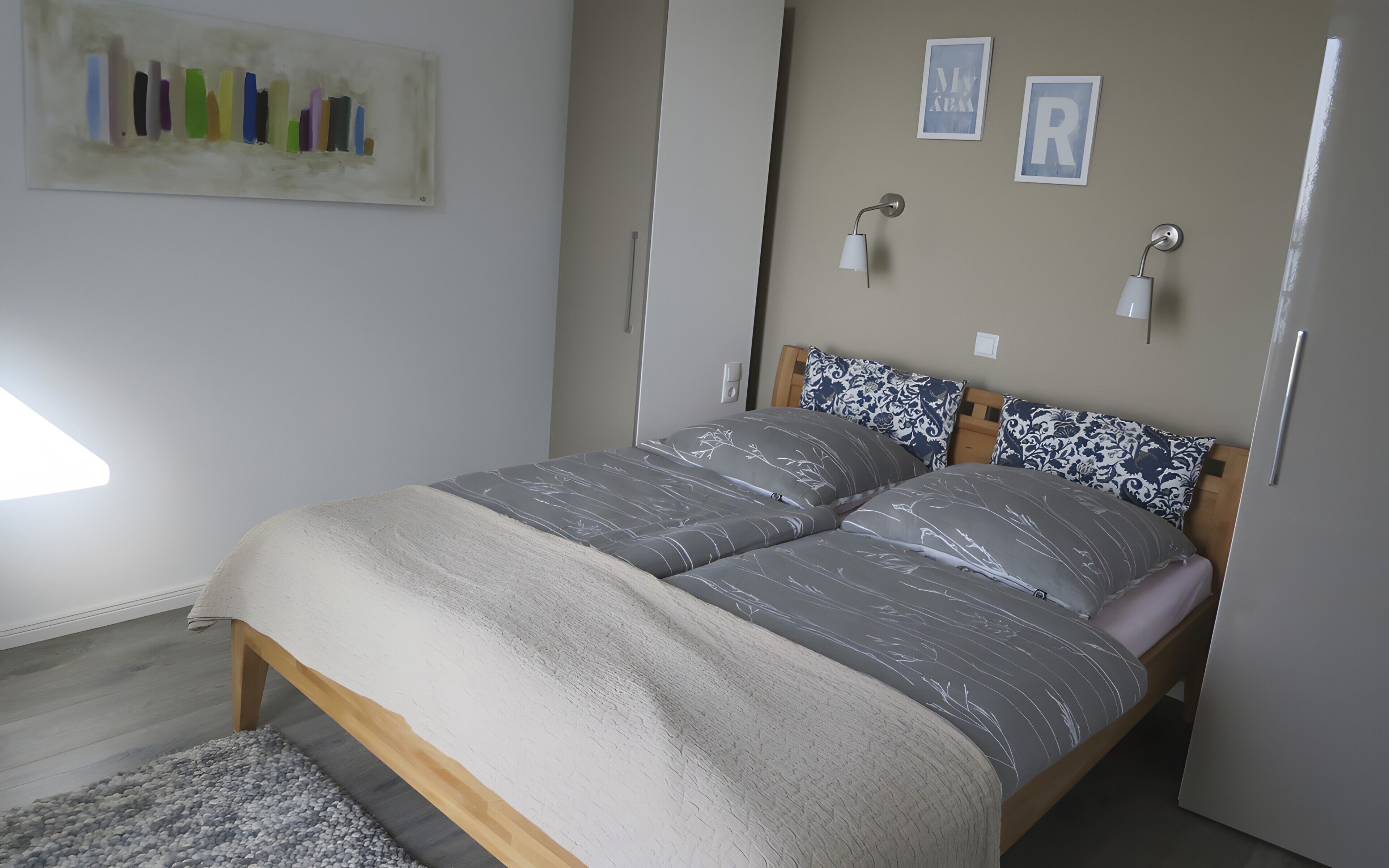 Une chambre à coucher avec un lit, une table de chevet, une lampe et des œuvres d’art murales.