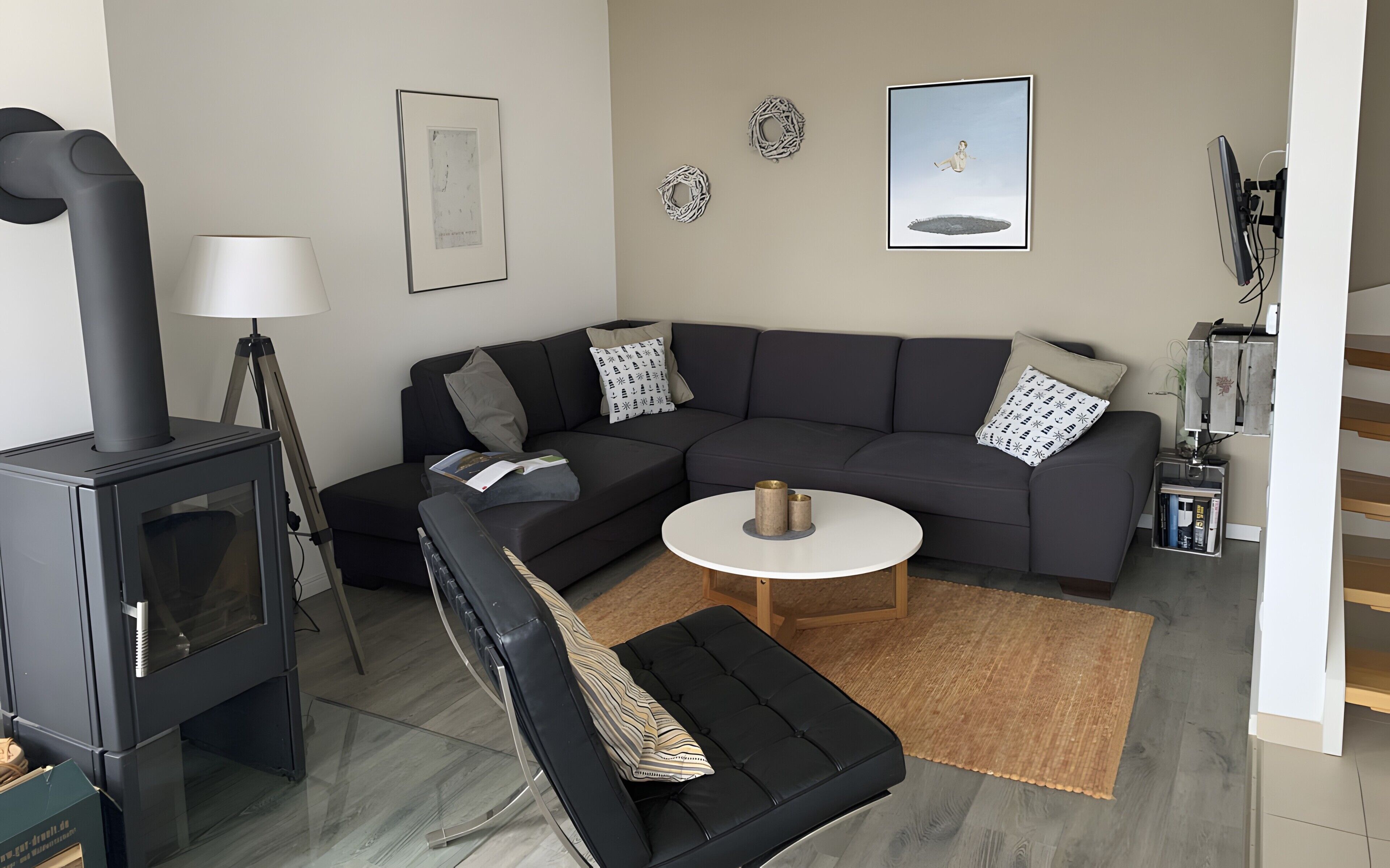 A modern living room with a sectional sofa, a round coffee table, a fireplace, and a wall-mounted TV.