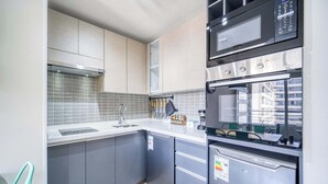 A modern kitchen with grey cabinets, a stainless steel refrigerator, a microwave, and a built-in oven. - Central Isabel II with Pool, Wifi & AC near Metro Santa Isabel (Santiago)