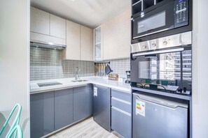 A modern kitchen with grey cabinets, a stainless steel refrigerator, a microwave, and a built-in oven. - Central Isabel II with Pool, Wifi & AC near Metro Santa Isabel (Santiago)