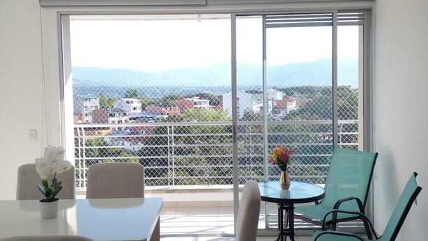 Ein Balkon mit Tisch, Stühlen und Blick auf eine Stadtlandschaft.