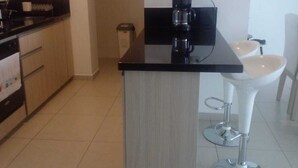 Eine kleine Küche mit einer Kaffeemaschine, einem Spülbecken und einem weißen Barhocker.