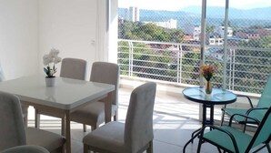 Eine moderne Wohnung mit Balkon, einem Essbereich mit Tisch und Stühlen sowie Blick auf die Stadt.