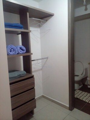 Un baño con inodoro, toallero y estante con toallas dobladas.