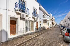 Une rue pavée bordée de bâtiments blancs, dont certains sont dotés de balcons et de fenêtres.