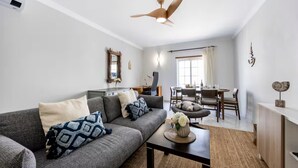 Ein modernes Wohnzimmer mit grauem Sofa, einem Couchtisch und einem Deckenventilator.