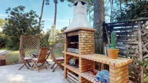 An outdoor patio with a brick barbecue grill, a pool, and a wooden fence. - Luxury Villa Aroeira (Setúbal)