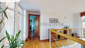A spacious room with wooden flooring, a staircase, and large windows. - Luxury Villa Aroeira (Setúbal)