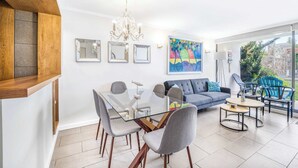 A modern living room with a glass dining table, grey chairs, a blue sofa, and a colorful abstract painting. - Central Reñaca W / Garden First Floor near Reñaca (Viña del Mar)