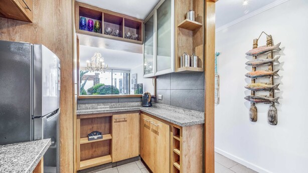 A modern kitchen with wooden cabinets, a stainless steel refrigerator, and a granite countertop. - Central Reñaca W / Garden First Floor near Reñaca (Viña del Mar)