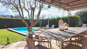 Ein überdachter Außenbereich mit Pool, Liegestühlen und Korbmöbeln.
