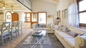 Ein Wohnzimmer mit einer Couch, Sesseln, einem Couchtisch und einem Essbereich mit Tisch und Stühlen.
