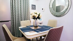 Un coin repas comprenant une table, des chaises, un vase de fleurs, un miroir fixé au mur et un panneau affichant une citation inspirante.