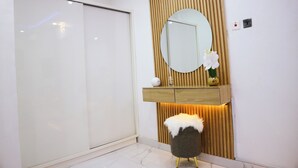 Une salle de bain moderne avec une porte coulissante, un meuble-lavabo en bois doté d’un miroir et un petit tabouret moelleux.
