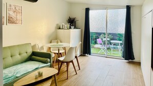 Una sala de estar moderna con un sofá verde, una mesa de comedor con sillas, y una cocina con electrodomésticos.