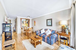 Ein gemütliches Wohnzimmer mit einer Couch, einem Holztisch und einem Essbereich mit Stühlen und Tisch.