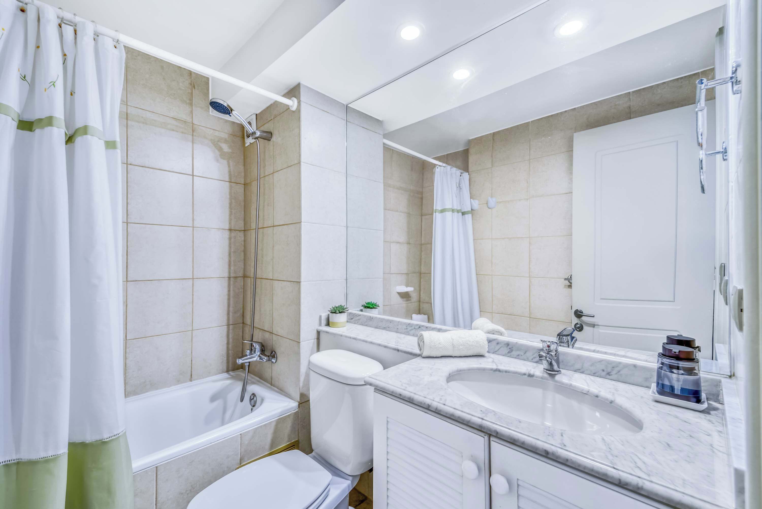 Une salle de bain moderne équipée d’une baignoire, de toilettes et d’un meuble-lavabo avec un grand miroir.