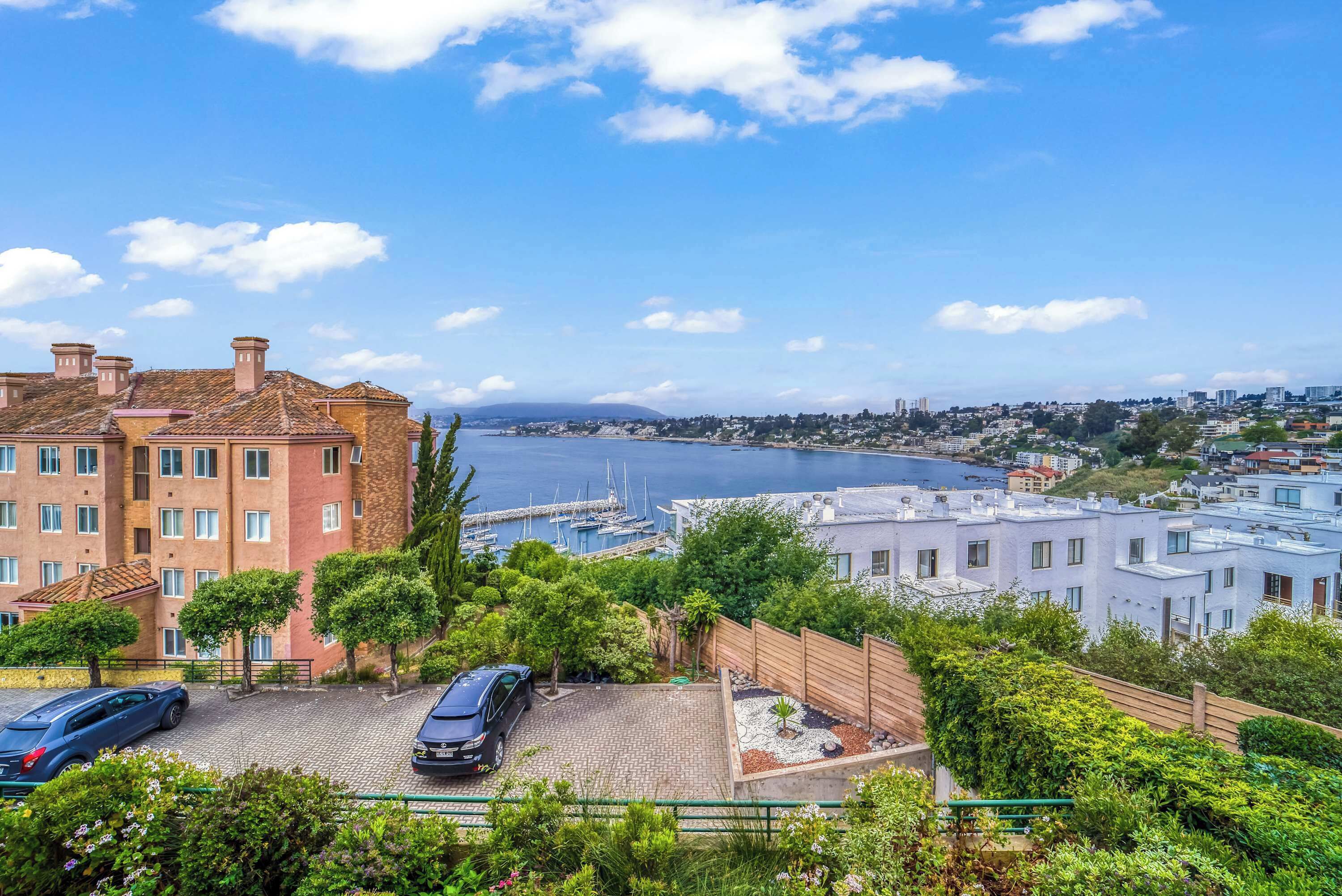 A residential area with a marina, a parking lot, and a view of the city across the water.