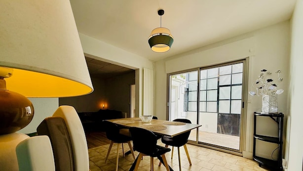 En matplats med ett bord och stolar, en lampa och utsikt genom en glasdörr.