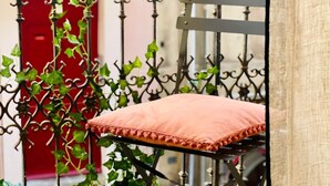 A metal chair with a cushion, surrounded by a wrought iron fence with climbing plants. - "Ribot" Coquet studio in the heart of Sète, Air conditioning & Wifi (Sète)