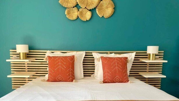 A hotel room with a bed, two pillows, a wooden headboard, and a wall decoration. - "Tango" T2 Air-conditioned, Town-centre, Parking, Wifi (Sète)