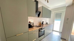 A modern kitchen with grey cabinets, a wooden countertop, and a built-in oven. - "Tango" T2 Air-conditioned, Town-centre, Parking, Wifi (Sète)