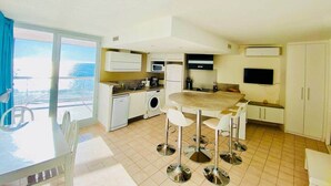 A compact kitchen with a dining area, a washing machine, and a TV. - "578" Superb T2 Sea Front, Parking, Air Conditioning (Sète)